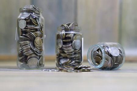 Accumulated coins stacked in glass jars on the floor