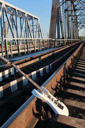 white electric guitar on the railroad tracks and industrial gray stoneの写真素材