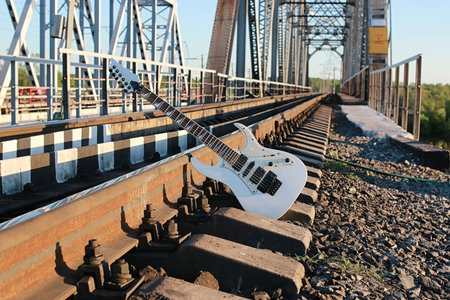 white electric guitar on the railroad tracks and industrial gray stone