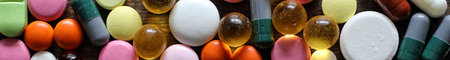 Medical background of various colorful medications on a textured wooden