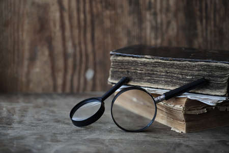 Old books on a wooden table and glass magnifierの写真素材