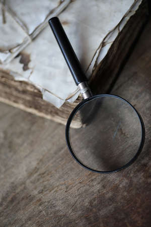 Old books on a wooden table and glass magnifierの写真素材