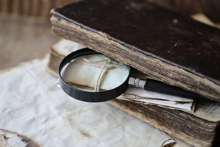Old books on a wooden table and glass magnifierの写真素材