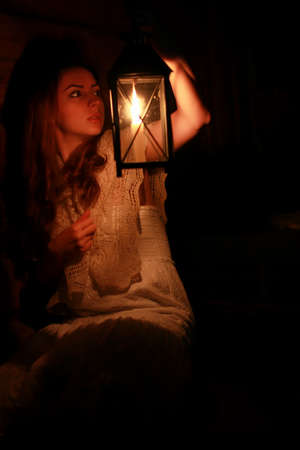 woman with candle lamp dark night indoorの写真素材