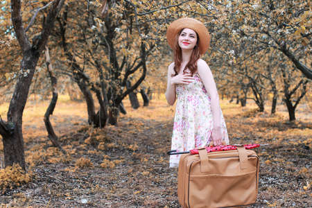girl with leather suitcase for travel in the autumn park on a walkの写真素材