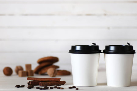 coffe in a white paper cup and beans on a tableの写真素材