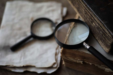 Old books on a wooden table and glass magnifierの写真素材