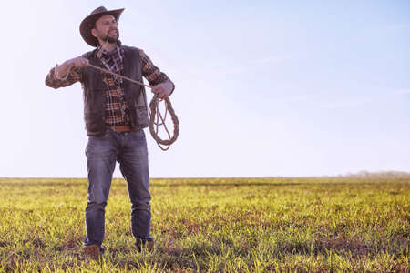 Cowboy standing in a field at sunsetの写真素材