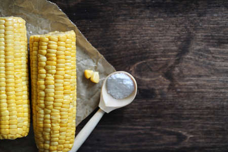 Boiled corn cob with salt on a woodの写真素材