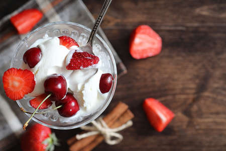 Yoghurt with fresh juicy strawberries and cherries on a wooden tableの写真素材