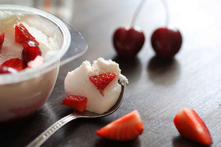 Yoghurt with fresh juicy strawberries and cherries on a wooden tableの写真素材