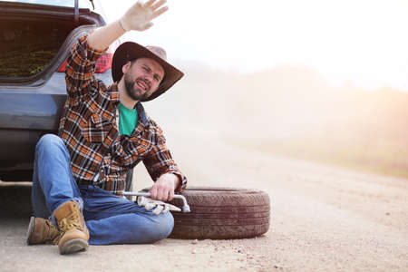 Man is sitting on the road by the carの写真素材