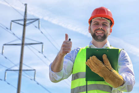 Electrician working in a helmet wearing gloves stand in a fieldの写真素材