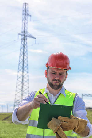 Electrician working in a helmet wearing gloves stand in a fieldの写真素材
