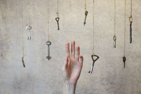 hand stretching for one of the many old vintage keys hanging on threadsの写真素材