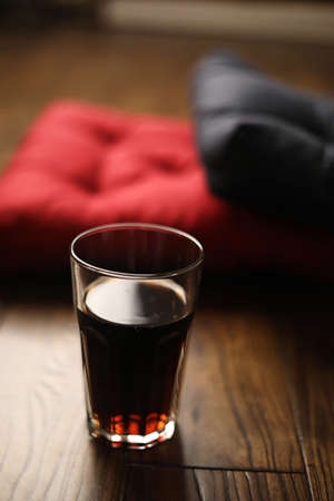 Pillows on a wooden parquet floor and a drink in a glass cupの写真素材