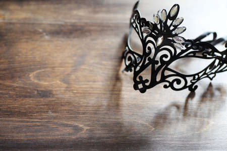 Black mask on the wooden background with space for textの写真素材