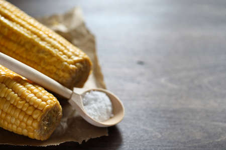Boiled corn cob with salt on a wooden tableの写真素材