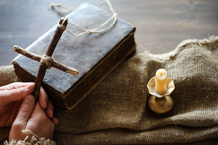 Ancient religious book and wooden cross on the background of a wooden and burlapの写真素材