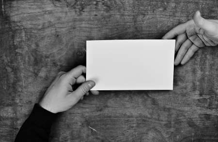 monochrome photo male hands holding a white blank sheet of paperの写真素材
