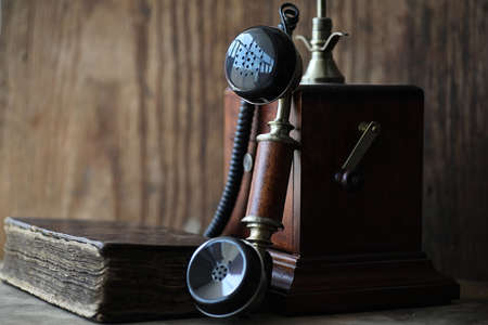 Old telephone and retro book on a wooden tableの写真素材