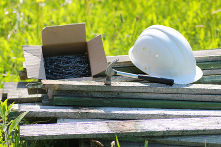 Construction materials lie on the grass hammer and helmet