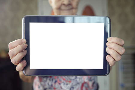 Elder woman holding in a hands tablet with empty screenの写真素材