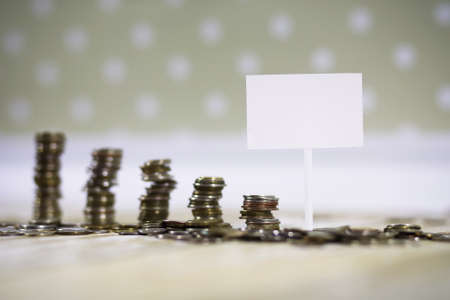 Accumulated coins stacked in piles on the wooden floorの写真素材
