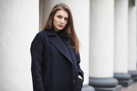 Beautiful girl in a coat in business downtownの写真素材