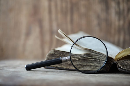 Old books on a wooden table and glass magnifierの写真素材
