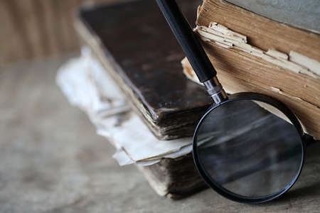 Old books on a wooden table and glass magnifierの写真素材