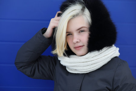 Young beautiful girl on a walk in winter at blue wallの写真素材