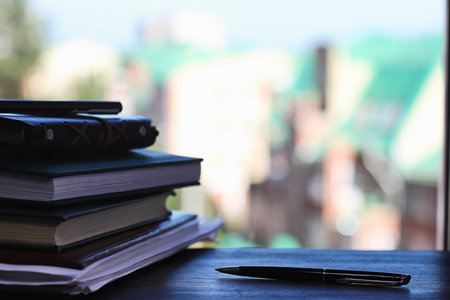 A stack of textbooks on the windowsill and writing utensils