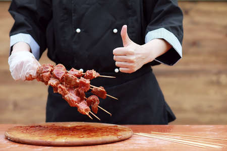 The cook cuts meat for cooking barbecue on the tableの写真素材