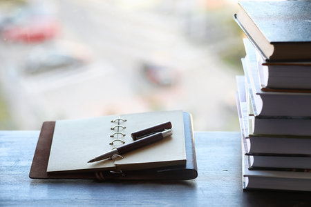 A stack of textbooks on the windowsill and writing utensils