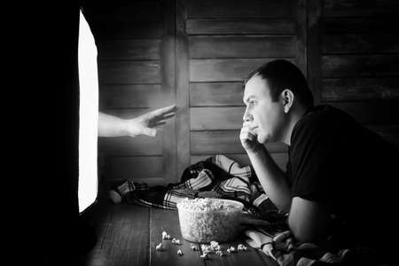 Watching a horror on TV black and whiteの写真素材