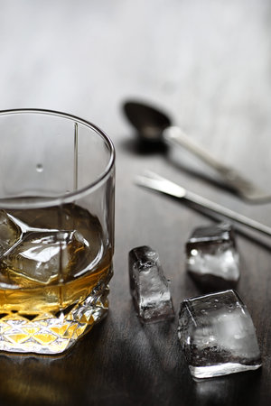 Whiskey in a glass and pieces of ice on a wood