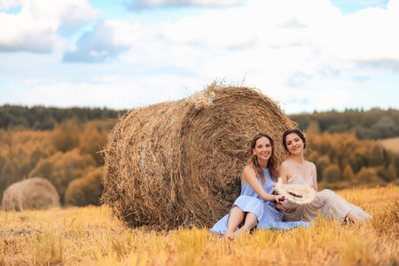 Two girls in dresses in autumn fieldの写真素材