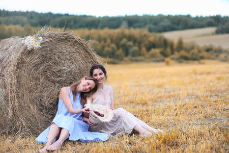 Two girls in dresses in autumn fieldの写真素材