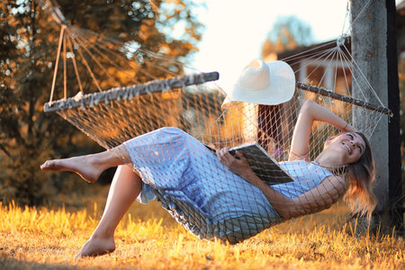 Beautiful girl in hammock reading a bookの写真素材