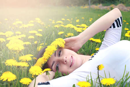 girl resting on a sunny day in meadow of yellow dandelionsの写真素材
