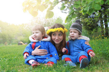 young twins sitting on green meadow in the early springの写真素材