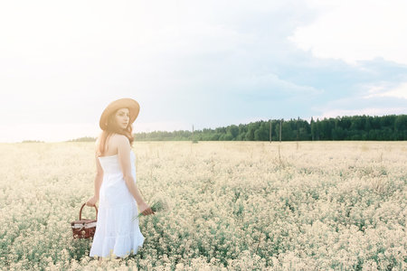 Girl in white dress in a field of yellow flowers blossomingの写真素材