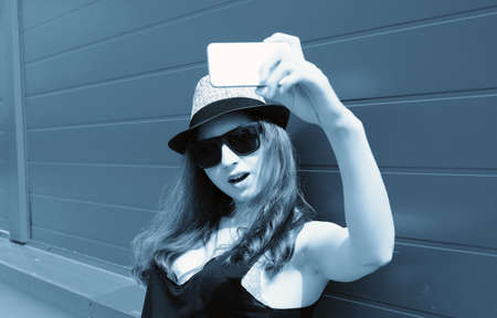 Cute girl hipster in a light hat and sunglasses on a summer dayの写真素材