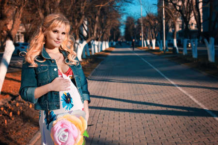 A pregnant woman posing at a city park in autumn dayの写真素材