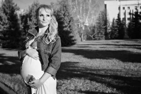 A pregnant woman in the city park in autumn dayの写真素材