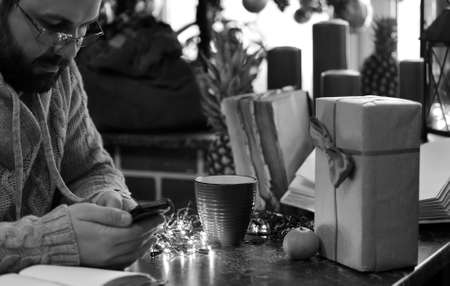 A monochrome photo of a bearded man writing a Christmas wish on a tableの写真素材