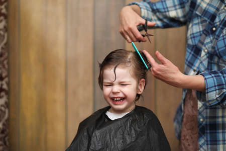 A little boy is trimmed in the hairdressers bright emotions onの写真素材