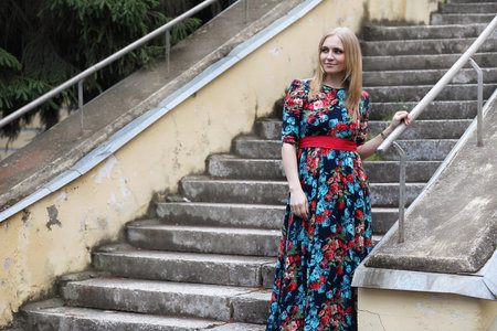A girl in flowery dress standing on the stairs in the street