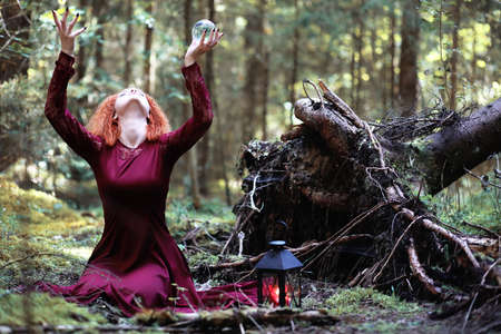 A red-haired witch holds a ritual with a crystal ballの写真素材